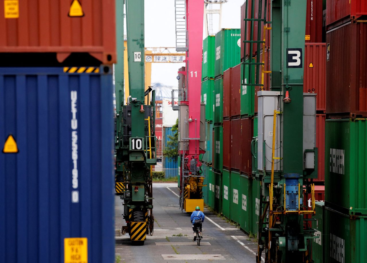 FILE PHOTO: A man in a bicycle drives past containers at an industrial port in Tokyo, Japan, May 22, 2019. REUTERS/Kim Kyung-Hoon