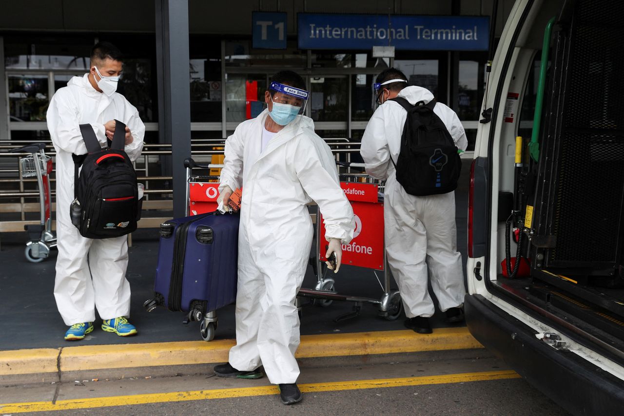 FILE PHOTO: Travellers in personal protective equipment load luggage into a taxi outside the international terminal at Sydney Airport, as countries react to the new coronavirus Omicron variant amid the coronavirus disease (COVID-19) pandemic, in Sydney, Australia, November 29, 2021.  REUTERS/Loren Elliott