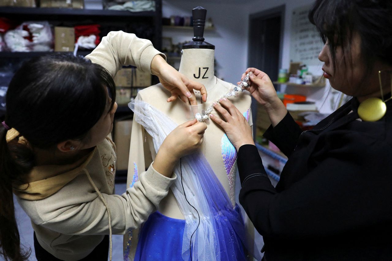 Costume designer Zhang Yifan and a tailor work on a skating dress Yifan made for her sister, figure skating athlete Zhang Yixuan, at her studio in Beijing, China December 7, 2021. REUTERS/Tingshu Wang