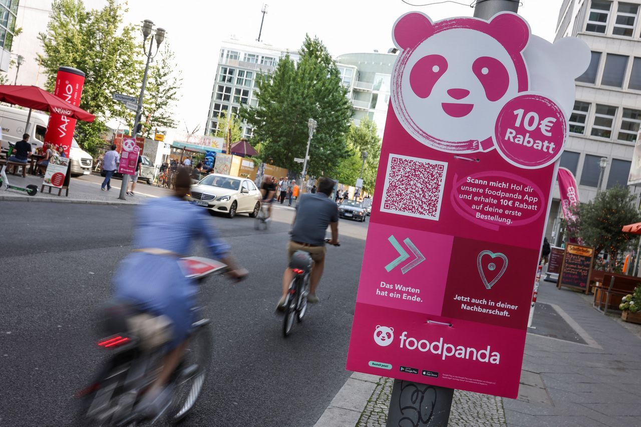 FILE PHOTO: Cyclists drive past an advertisement promoting the grocery delivery company "foodpanda", in Berlin, Germany, August 13, 2021. Picture taken August 13, 2021. REUTERS/Christian Mang