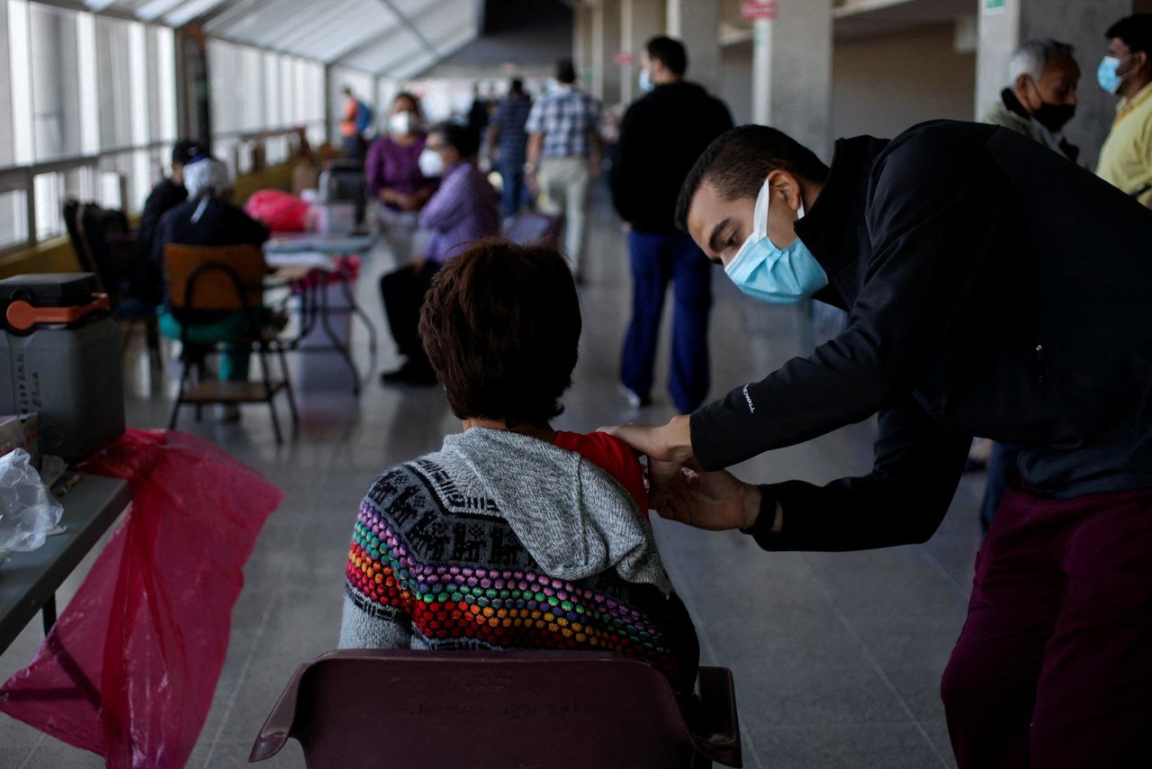 A woman receives a booster dose of a coronavirus disease (COVID-19) vaccine as the country seeks to counter the threat posed by the Omicron variant of the virus, at the sports center of the National Autonomous University of Honduras (UNAH) in Tegucigalpa, Honduras December 23, 2021. REUTERS/Fredy Rodriguez