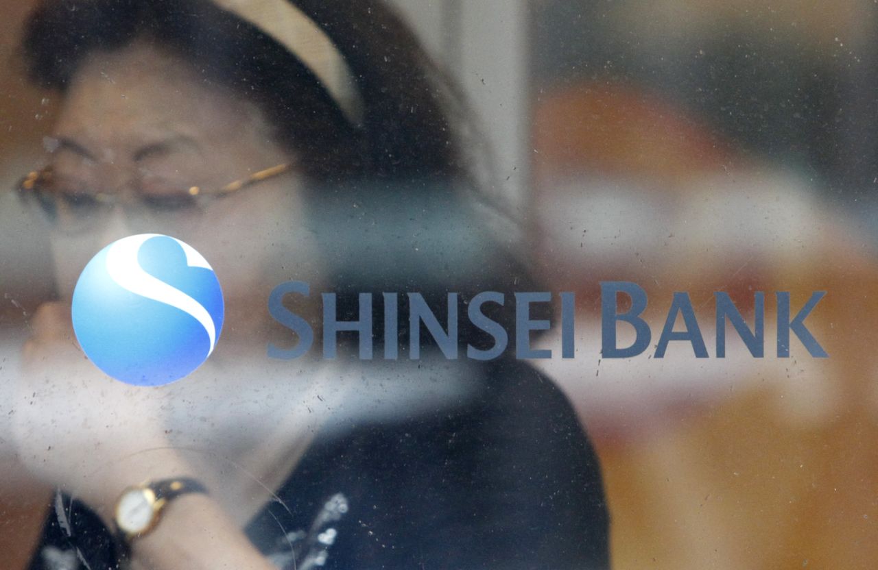 FILE PHOTO: A woman walks past a logo of the Shinsei Bank at its branch in Yokohama, south of Tokyo, June 23, 2010. REUTERS/Issei Kato