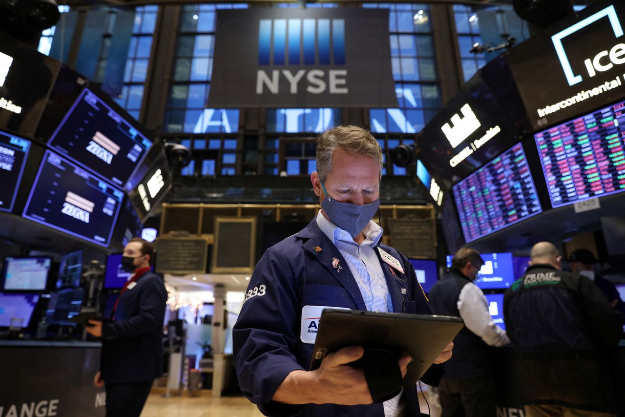 FILE PHOTO: A trader in a face mask works on the trading floor at the New York Stock Exchange (NYSE) as the Omicron coronavirus variant continues to spread in Manhattan, New York City, U.S., December 20, 2021. REUTERS/Andrew Kelly