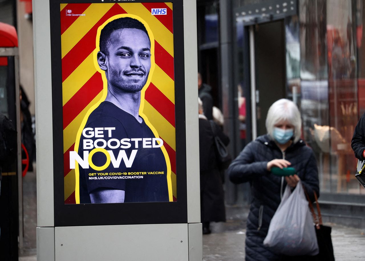 A woman walks past an advertising board encouraging people to get their booster vaccination, amid the coronavirus disease (COVID-19) outbreak in Liverpool, Britain, December 29, 2021. REUTERS/Phil Noble