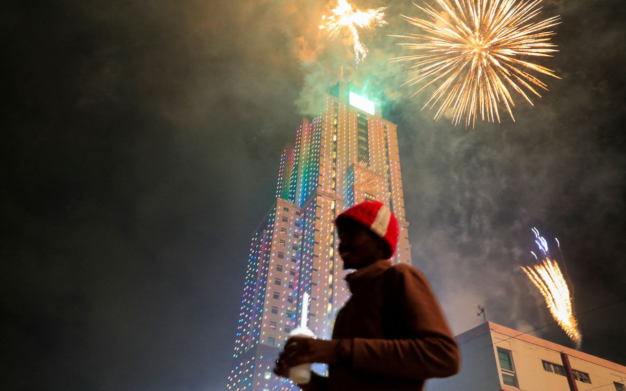 A reveller stands as fireworks explode over the UAP Old Mutual Tower during the New Year