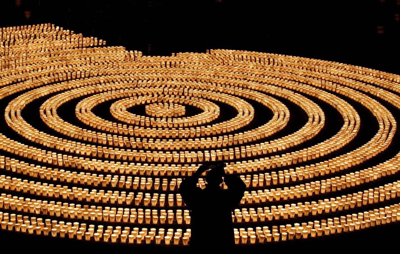 A staff wearing a protective mask, amid the coronavirus disease (COVID-19) outbreak, takes picture of 6,500 candle lights as he prepares for a ceremony to wish for overcoming the pandemic and good luck in the upcoming New Year at Hasedera Buddhist temple in Kamakura, south of Tokyo, Japan, December 31, 2021. REUTERS/Kim Kyung-Hoon
