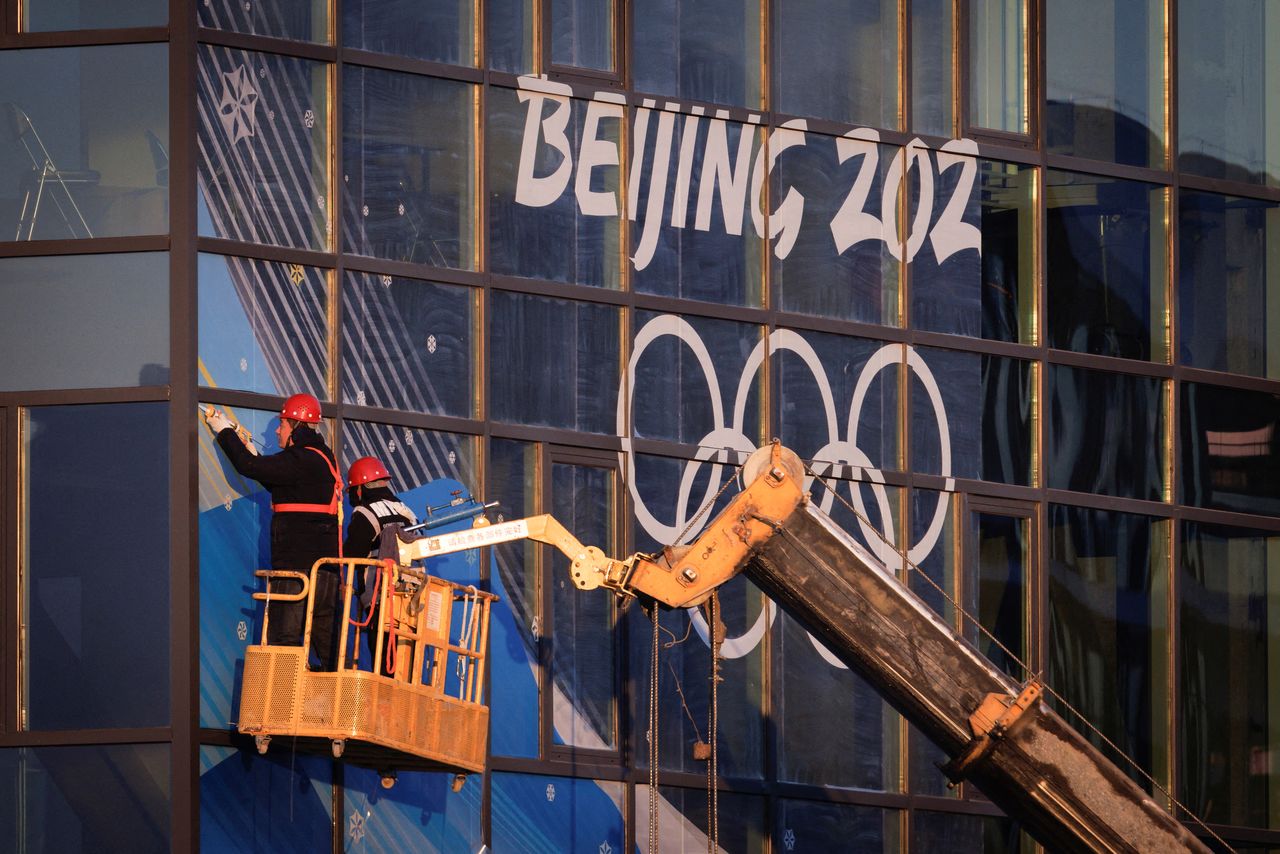 FILE PHOTO: Workers attach signage near Big Air Shougang, a competition venue for the Beijing 2022 Winter Olympics, at Shougang Park, the site of a former steel mill, in Beijing, China, December 28, 2021. Picture taken December 28, 2021. REUTERS/Thomas Peter