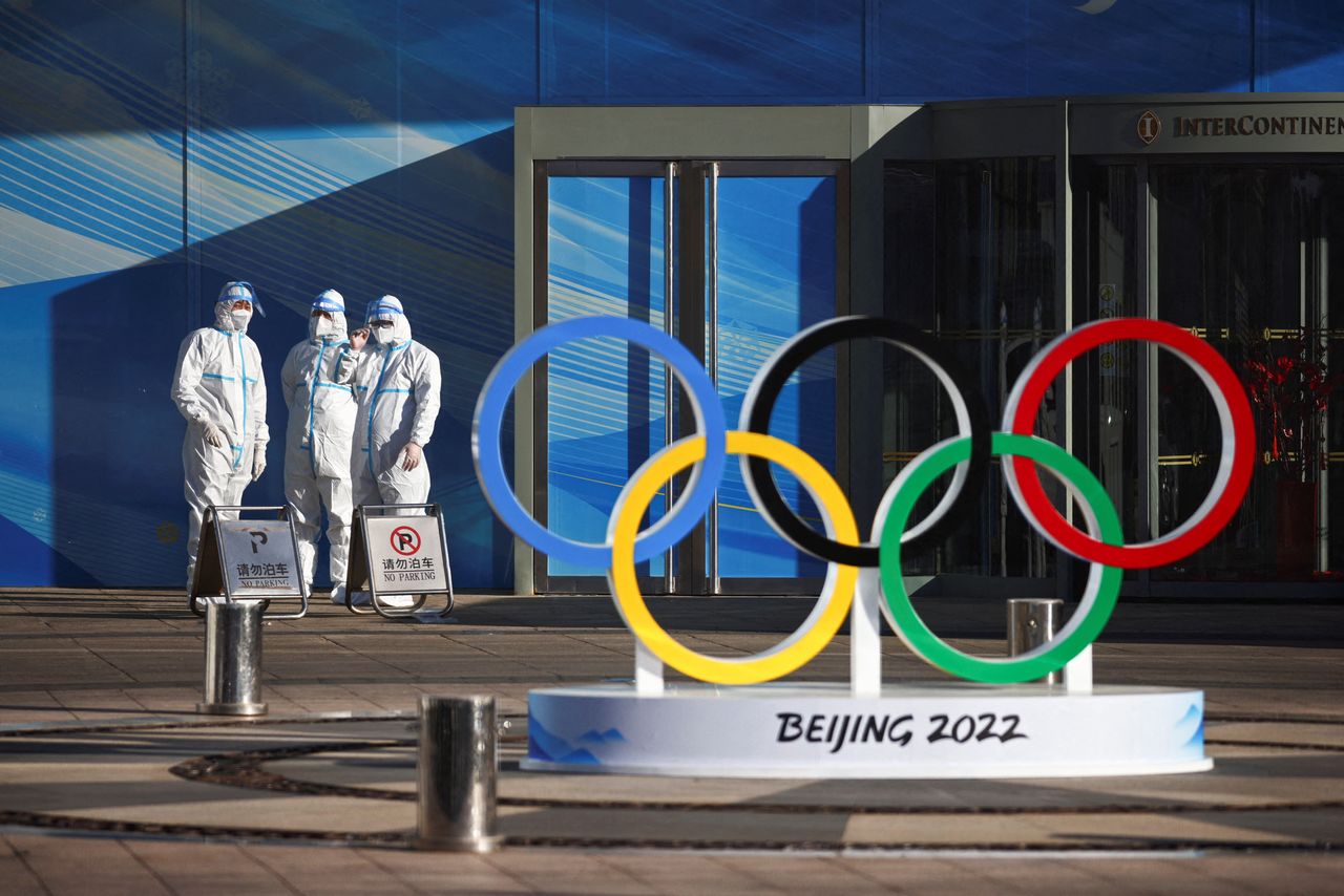 FILE PHOTO: Workers in PPE stand next to the Olympic rings inside the closed loop area near the National Stadium, or the Bird