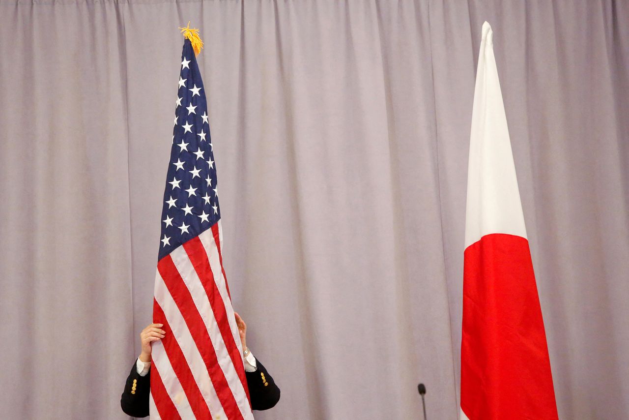 FILE PHOTO: A worker adjusts the U.S. flag before Japanese Prime Minister Shinzo Abe addresses media following a meeting with President-elect Donald Trump in Manhattan, New York, U.S., November 17, 2016. REUTERS/Andrew Kelly