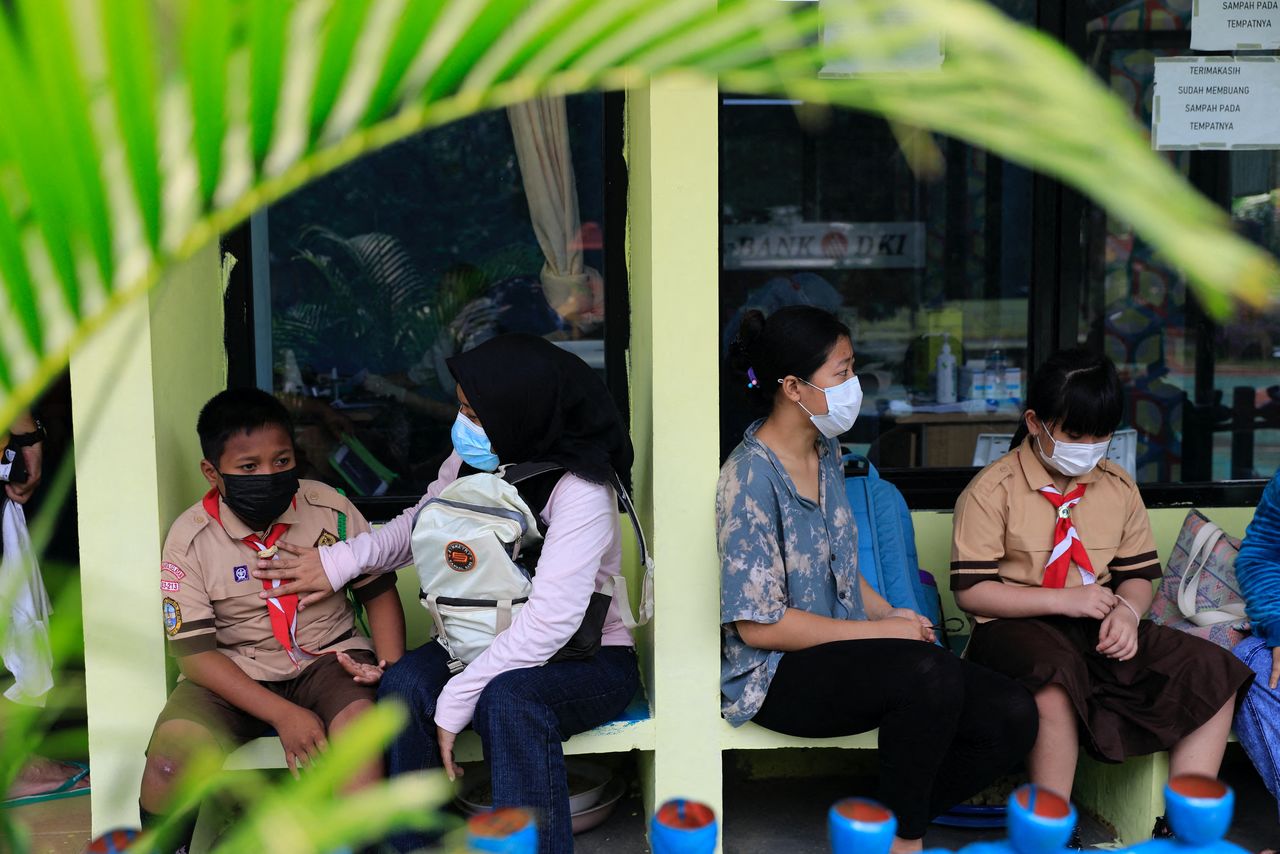 Children accompanied by their mothers wait for health screening before receiving a dose of China