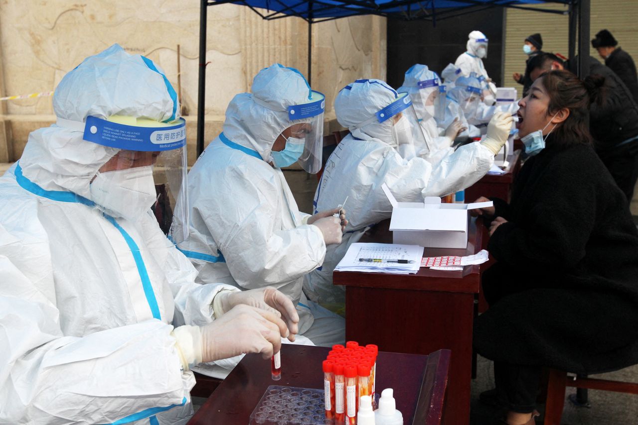 Medical workers in protective suits collect swabs for nucleic acid testing during a mass testing following cases of the coronavirus disease (COVID-19) in Xuchang, Henan province, China January 6, 2022. China Daily via REUTERS