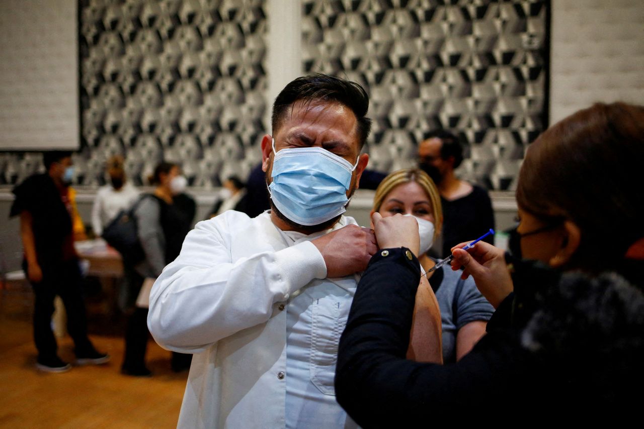 A health worker reacts while receiving a booster shot of the AstraZeneca coronavirus disease (COVID-19) vaccine, in Ciudad Juarez, Mexico January 6, 2022. REUTERS/Jose Luis Gonzalez