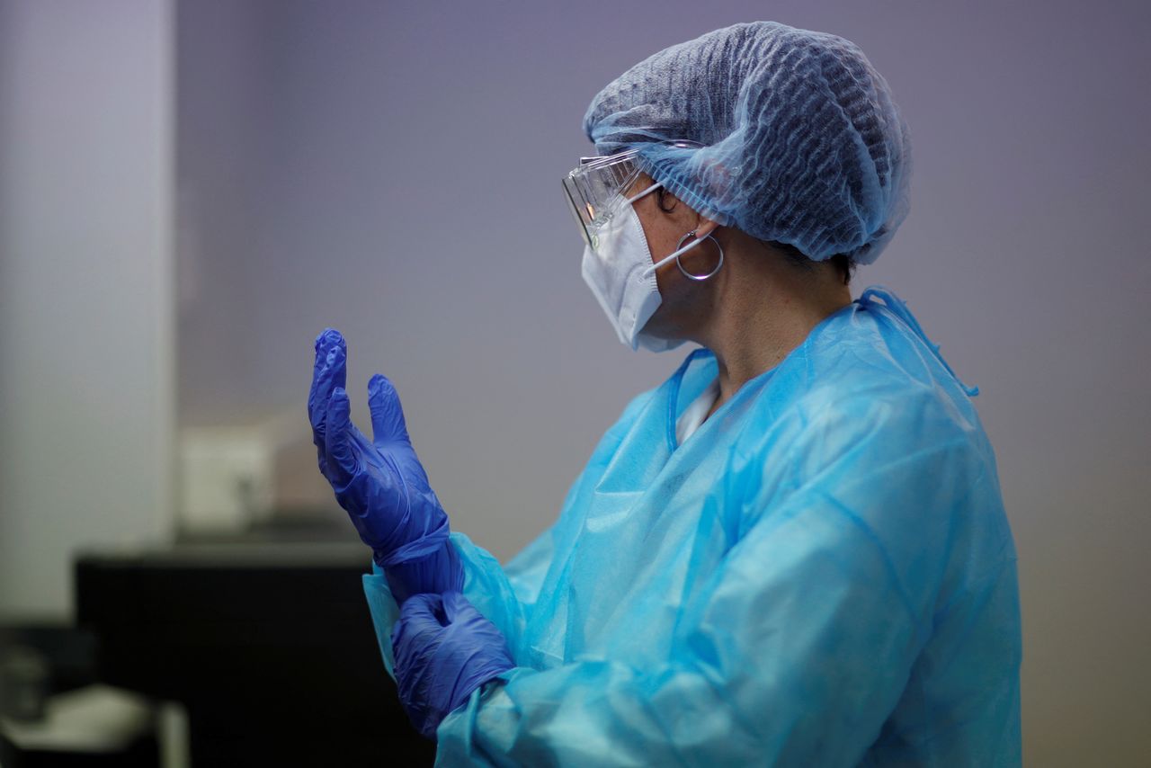 FILE PHOTO: A health worker, wearing a protective suit and a face mask, adjusts her gloves at a testing site for the coronavirus disease (COVID-19) in Thouare-sur-Loire near Nantes, France, September 29, 2020. REUTERS/Stephane Mahe