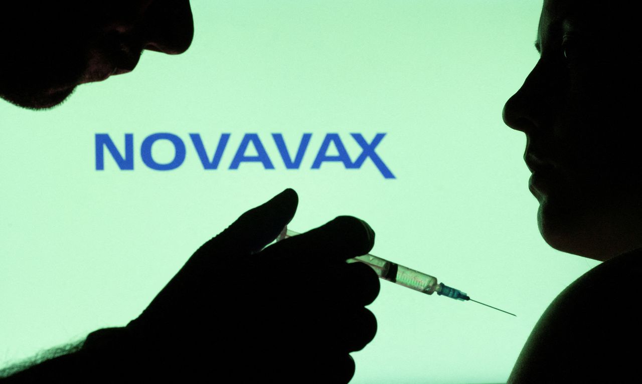 People pose with syringe with needle in front of displayed Novavax logo in this illustration taken, December 11, 2021. REUTERS/Dado Ruvic/Illustration/Files