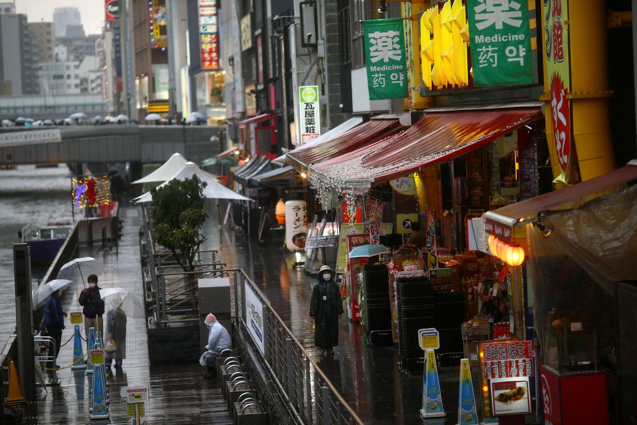 FILE PHOTO: A woman, wearing protective mask following an outbreak of the coronavirus disease (COVID-19), walks on an almost empty street in the Dotonbori entertainment district of Osaka, Japan, March 14, 2020. Pictured taken March 14, 2020. REUTERS/Edgard Garrido