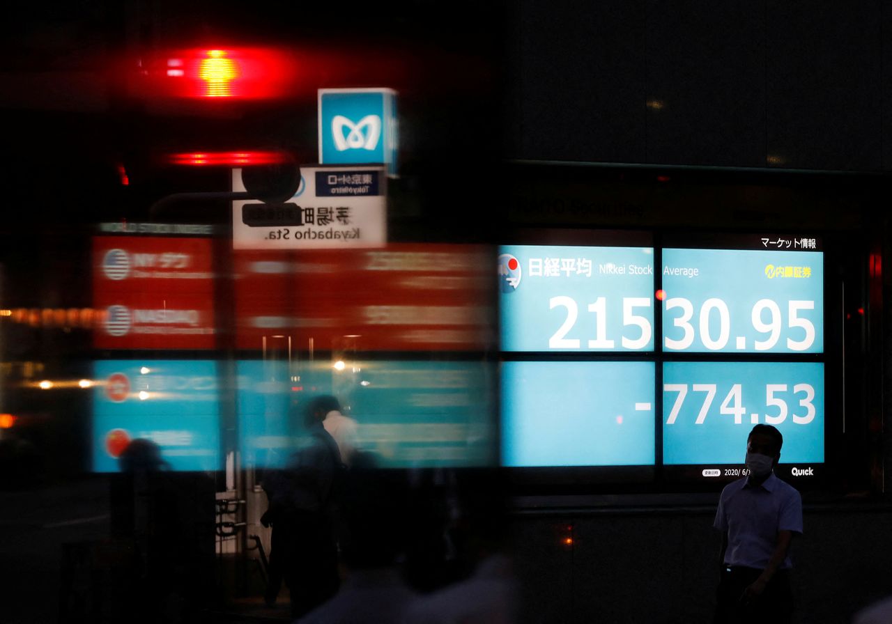 FILE PHOTO: A man wearing a protective face mask, following the coronavirus disease (COVID-19) outbreak, is silhouetted in front of a stock quotation board outside a brokerage in Tokyo, Japan, June 15, 2020. REUTERS/Kim Kyung-Hoon