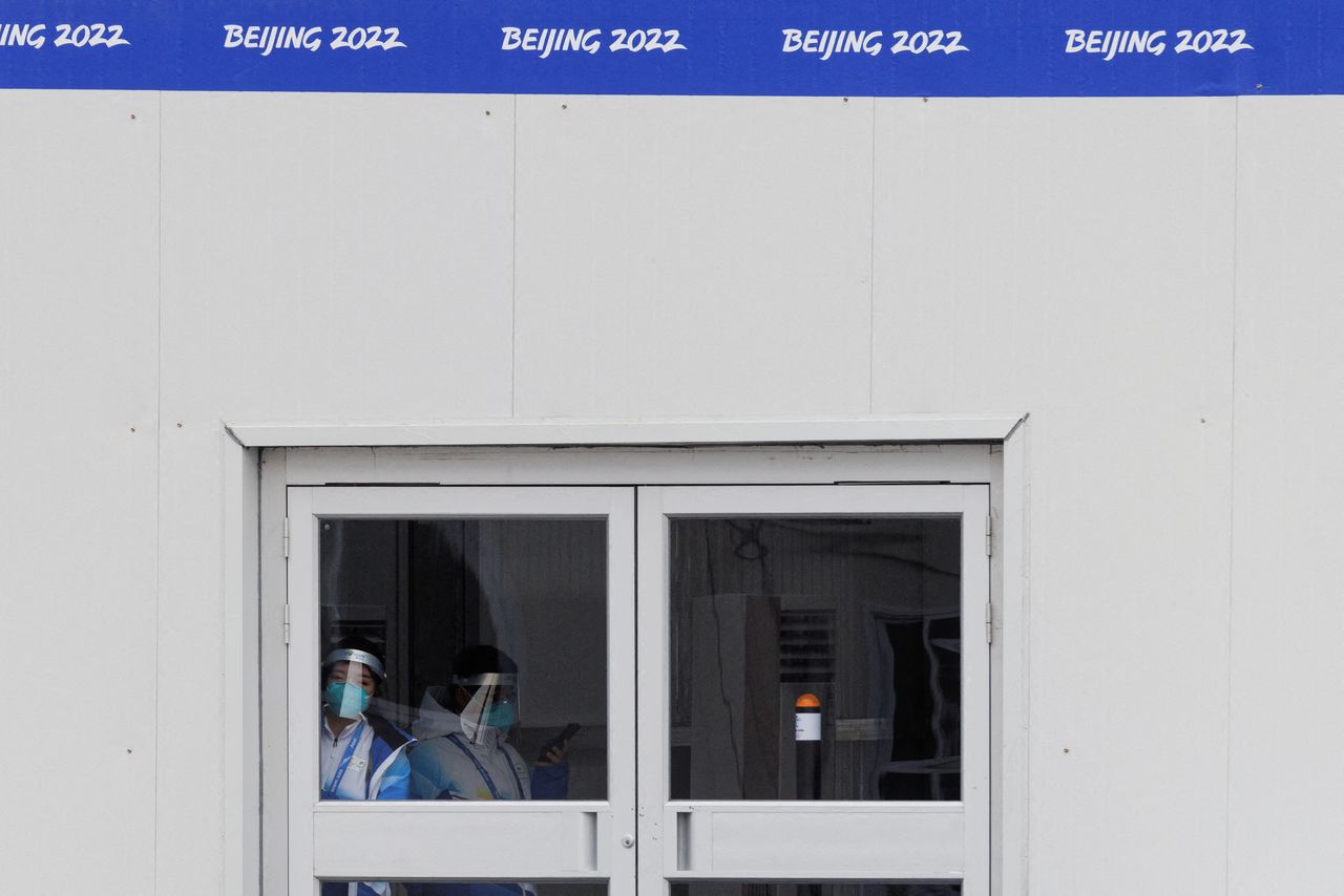 Volunteers stand in an entrance booth at the Main Media Center inside a closed loop area created to prevent the spread of the coronavirus disease (COVID-19) at the Beijing 2022 Winter Olympics, in Beijing, China, January 12, 2022. Picture taken January 12, 2022. REUTERS/Thomas Peter