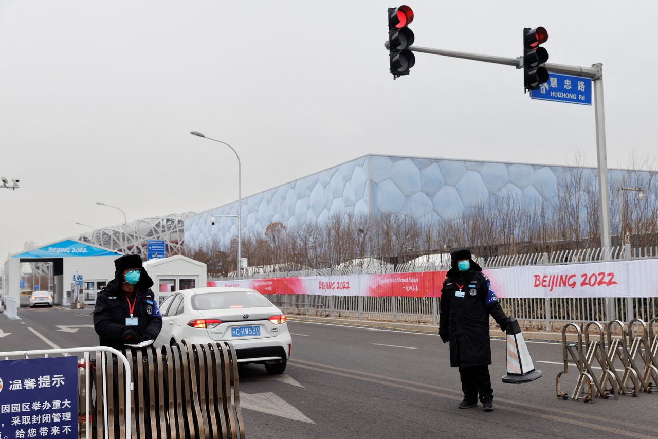 Security guards keep watch at a vehicle entrance to venues inside a closed loop area created to prevent the spread of the coronavirus disease (COVID-19) at the Beijing 2022 Winter Olympics, in Beijing, China, January 12, 2022. REUTERS/Thomas Peter