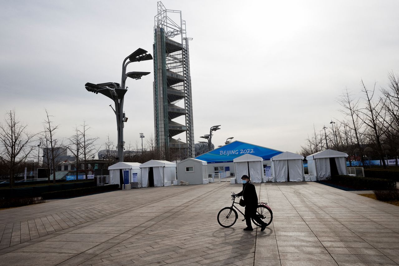 A man walks outside barriers that surround venues that are inside a closed loop area created to prevent the spread of the coronavirus disease (COVID-19) at the Beijing 2022 Winter Olympics, in Beijing, China, January 12, 2022. REUTERS/Thomas Peter