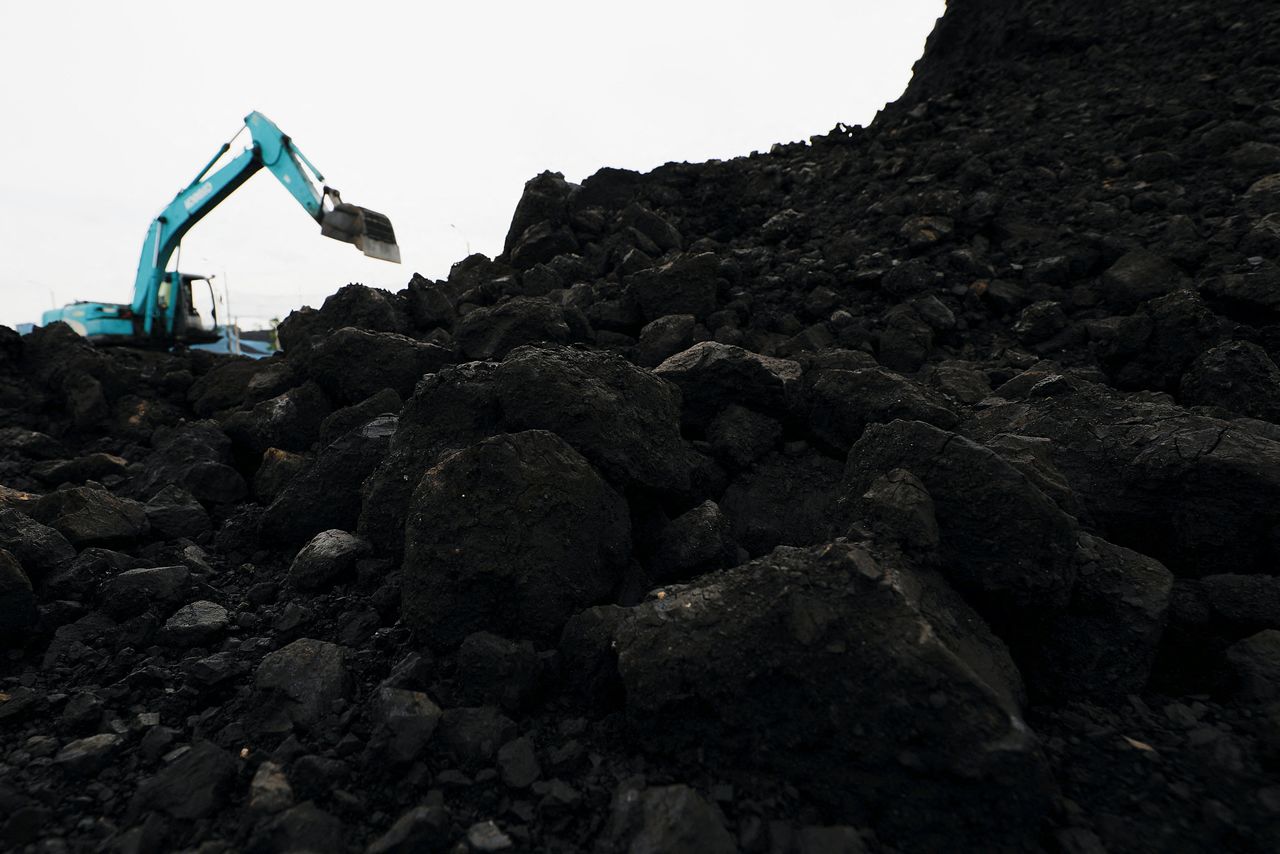 FILE PHOTO: Coal is seen as a heavy machinery unloads it from the barges into a truck to be distributed, at the Karya Citra Nusantara port in North Jakarta, Indonesia, January 13, 2022. REUTERS/Willy Kurniawan
