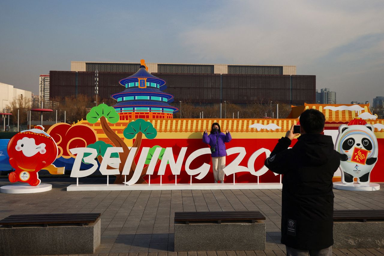 A woman has her picture taken in front of a Beijing 2022 installation near the closed loop "bubble" surrounding venues of the Beijing 2022 Winter Olympics in Beijing, China, January 18, 2022. REUTERS/Thomas Peter