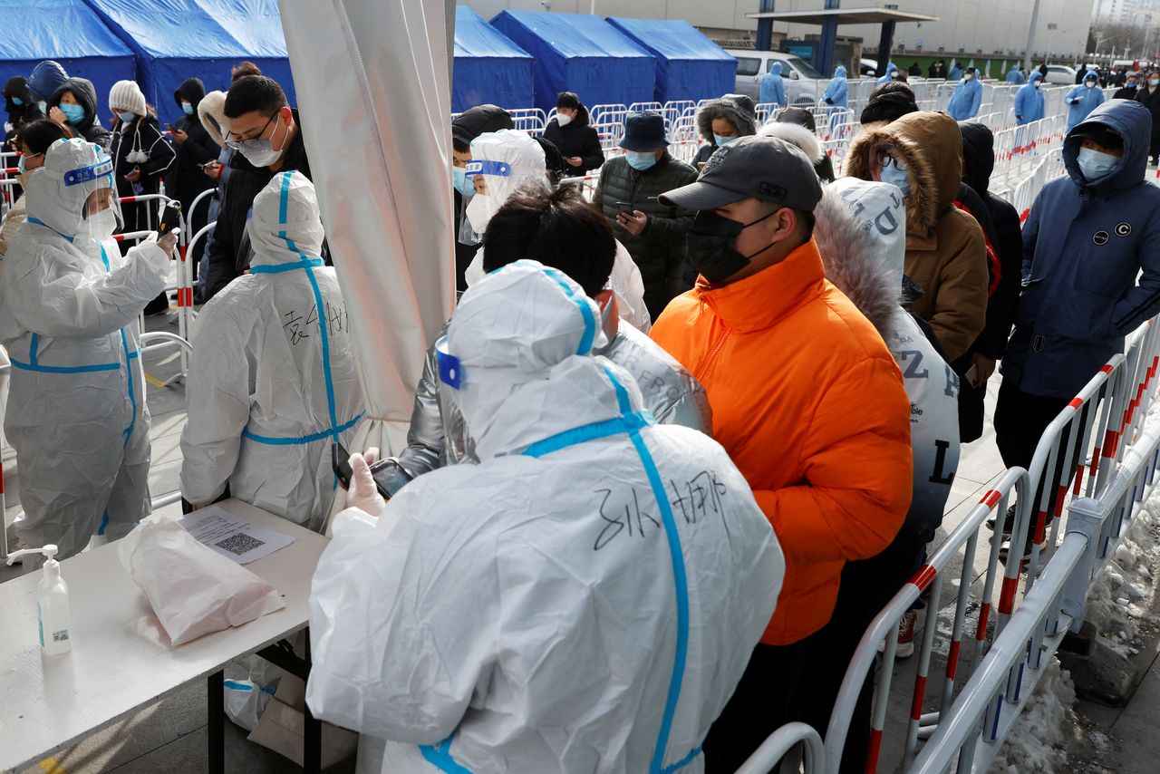 Staff members in protective suits help residents at a nucleic acid testing site outside a shopping mall, following the coronavirus disease (COVID-19) outbreak in Beijing, China January 26, 2022. REUTERS/Carlos Garcia Rawlins
