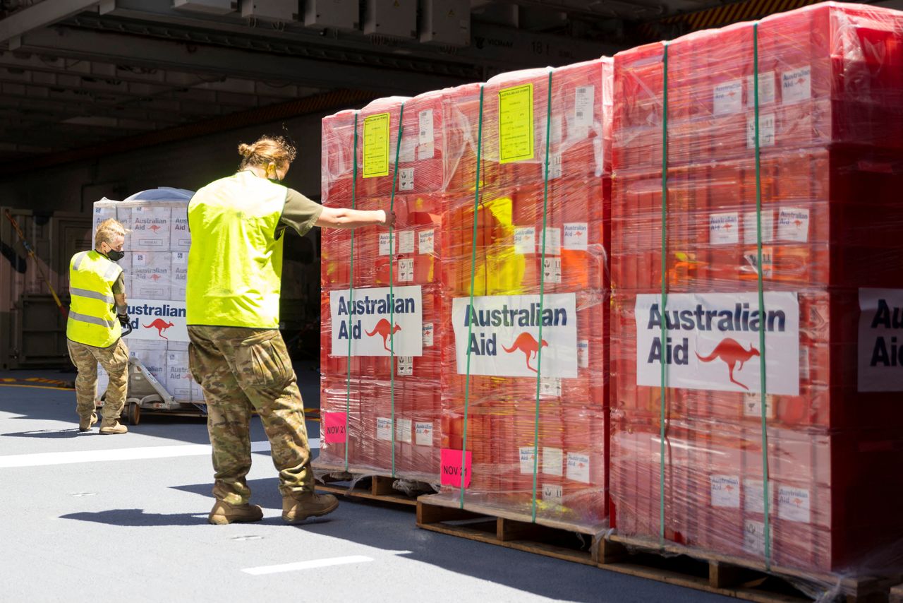 People prepare humanitarian aid as the HMAS Adelaide sails into the port of Nuku
