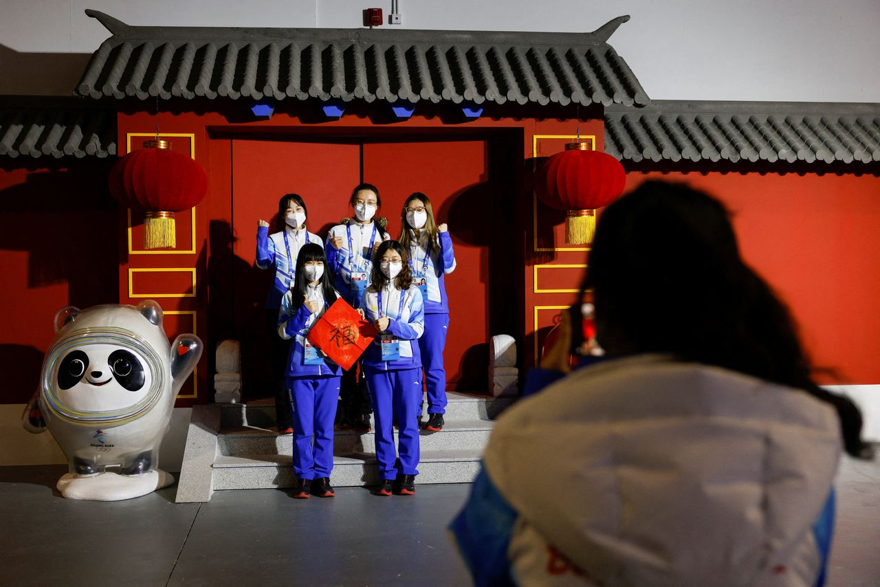 Volunteers pose for photo next to the installation of Bing Dwen Dwen and Shuey Rhon Rhon, mascots of the Beijing 2022 Winter Olympics and Paralympics, at the Main Press Centre ahead of the Beijing 2022 Winter Olympics, in Beijing, China January 26, 2022.  REUTERS/Tyrone Siu