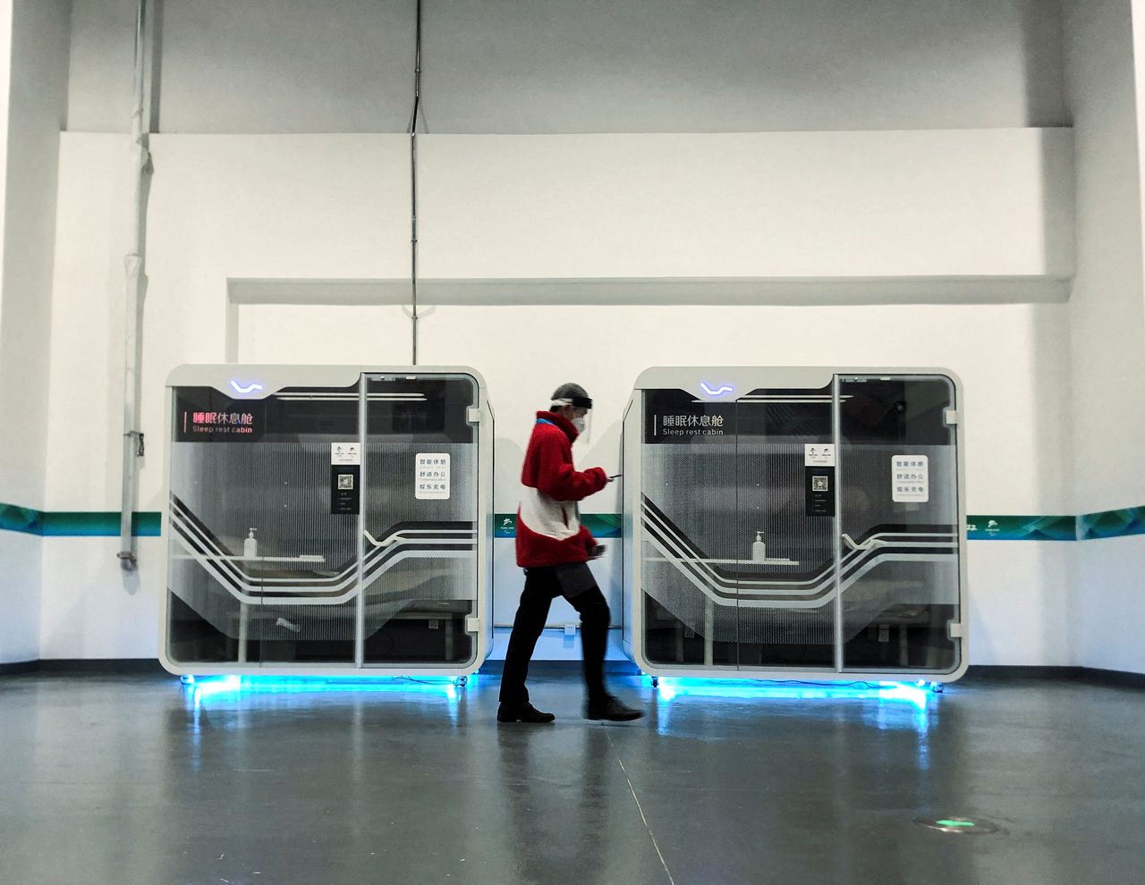 A man walking past sleeping cabins placed in the 2022 Winter Olympics main media centre in Beijing, China, January 30, 2022. REUTERS/Angie Teo