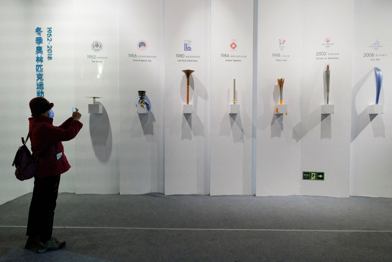 FILE PHOTO: A woman takes pictures of Olympic torches of past Games at an exhibition at the Capital Museum ahead of the Beijing 2022 Winter Olympics in Beijing, China, January 5, 2022. REUTERS/Thomas Peter