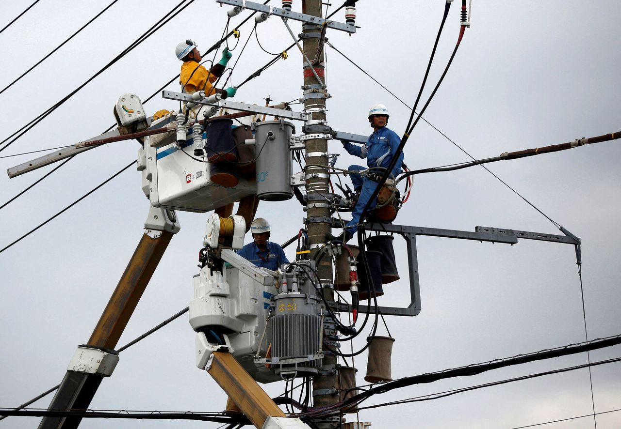 FILE PHOTO: Men work around an electric utility pole along the street in Urayasu, east of Tokyo October 9, 2014.  REUTERS/Issei Kato
