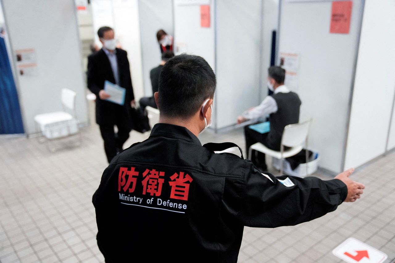 A staff of the Ministry of Defense guides local residents who received the booster shot of the Moderna coronavirus disease (COVID-19) vaccine at a mass vaccination center operated by Japanese Self-Defense Force, in Tokyo, Japan, January 31, 2022. Eugene Hoshiko/Pool via REUTERS