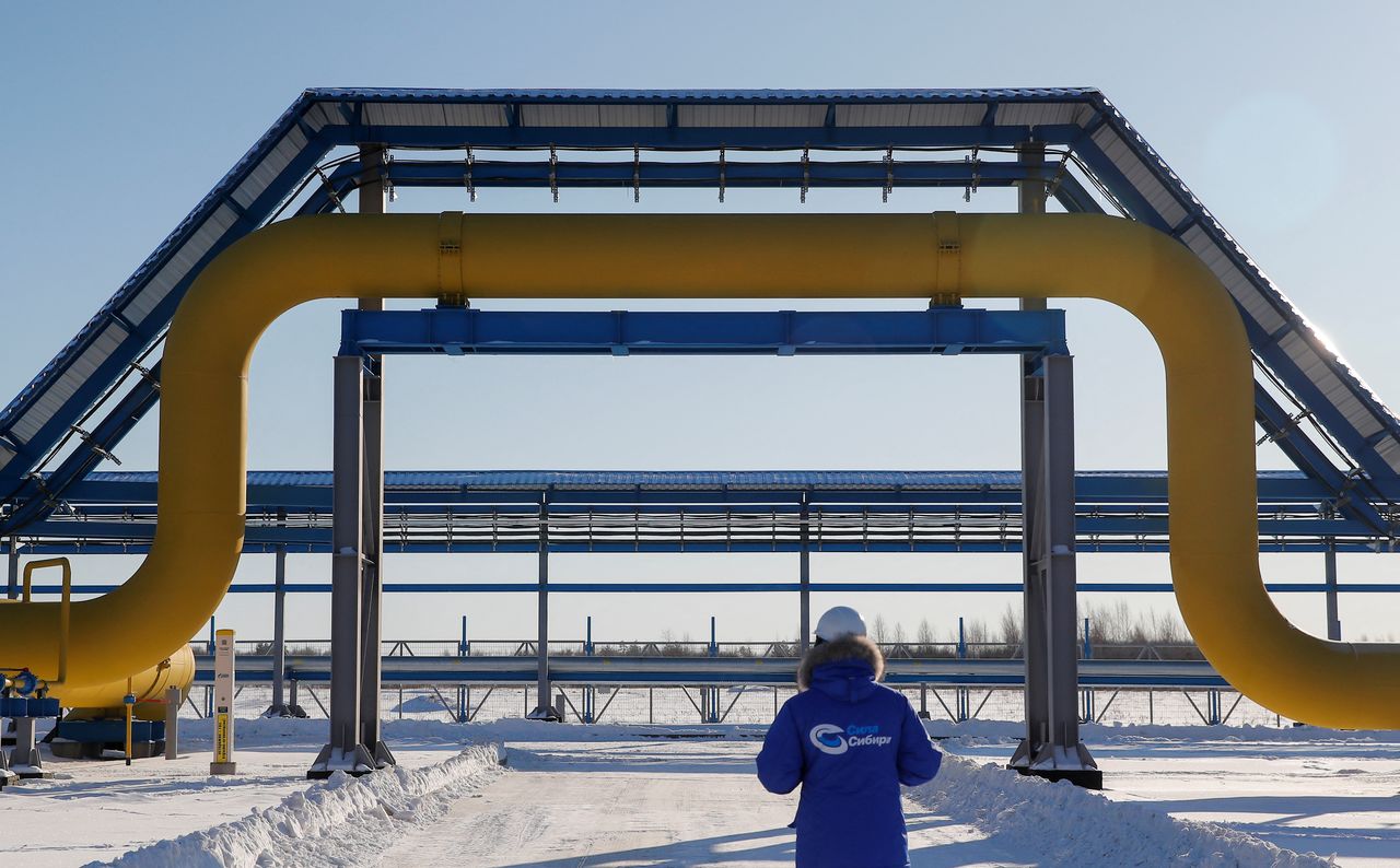FILE PHOTO: An employee in branded jacket walks past a part of Gazprom