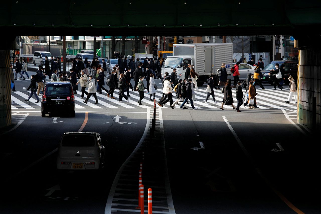 FILE PHOTO: People wearing protective face masks walk on a pedestrian crossing, amid the coronavirus disease (COVID-19) pandemic, in Tokyo, Japan January 19, 2022. REUTERS/Issei Kato
