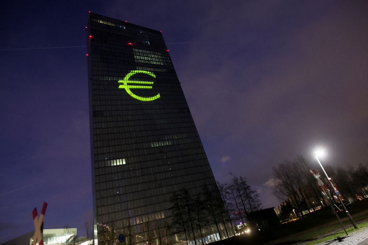 FILE PHOTO: A Euro sign is seen moments before a symphony of light consisting of bars, lines and circles in blue and yellow, the colours of the European Union, illuminates the south facade of the European Central Bank (ECB) headquarters in Frankfurt, Germany, December 30, 2021. REUTERS/Wolfgang Rattay/File Photo