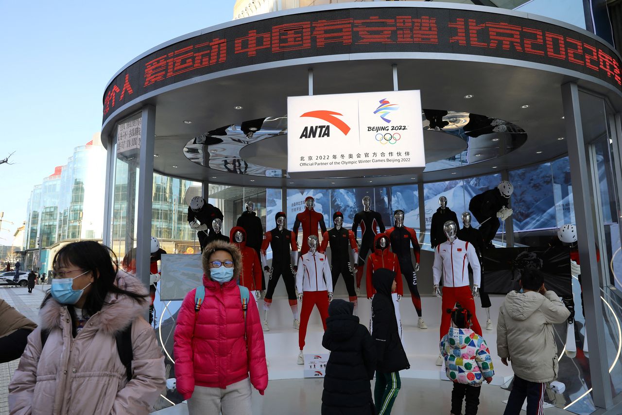 People walk past an Anta pop-up booth displaying the company