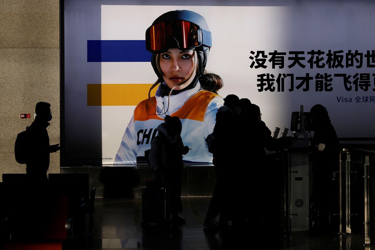 People line up to board a train near an image of freestyle skier Eileen Gu at a railway station ahead of the Beijing 2022 Winter Olympics, during the Chinese Lunar New Year holiday, in Beijing, China February 3, 2022. REUTERS/Tingshu Wang