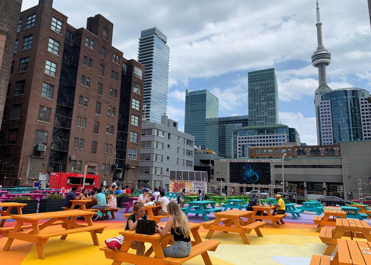 People sit at picnic tables in the RendezViews outdoor patio project in Toronto, Canada, June 20, 2021.  REUTERS/Kyaw Soe Oo