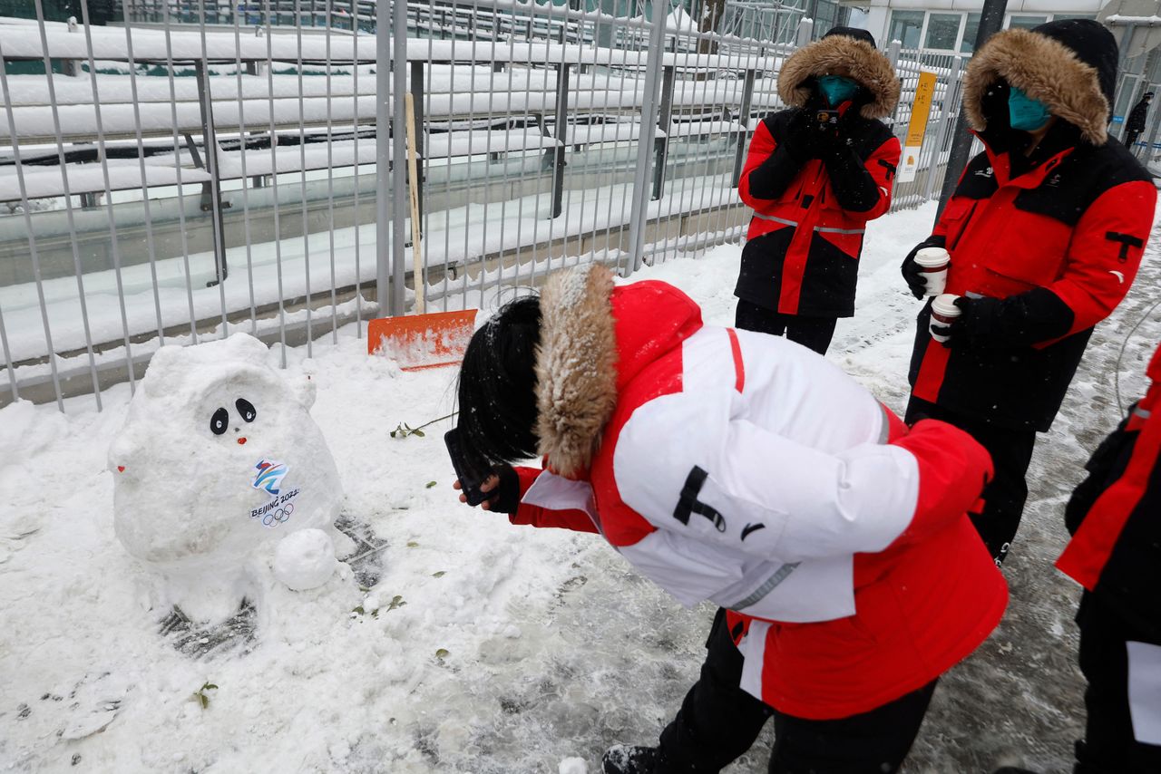 Workers create a Bing Dwen Dwen mascot snowman outside National Indoor Stadium during preliminary men