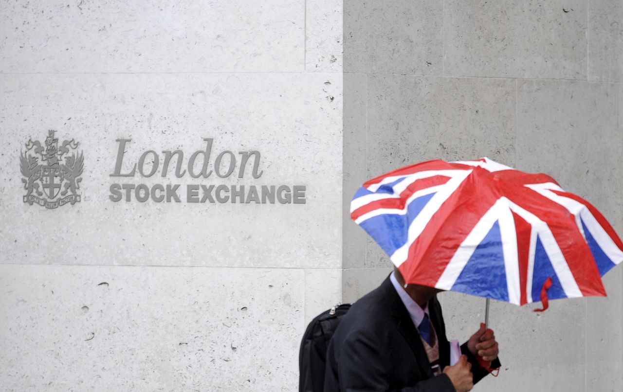 FILE PHOTO: A worker shelters from the rain under a Union Flag umbrella as he passes the London Stock Exchange in London, Britain, October 1, 2008.  REUTERS/Toby Melville/File Photo