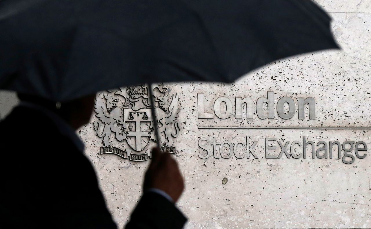 FILE PHOTO: A man shelters under an umbrella as he walks past the London Stock Exchange in London, Britain, August 24, 2015. REUTERS/Suzanne Plunkett/File Photo