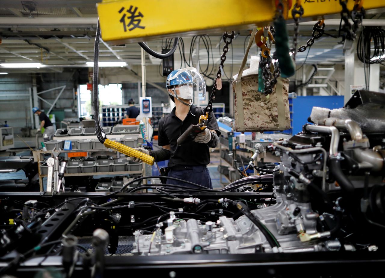 FILE PHOTO: An employee wearing a protective face mask and face guard works on the automobile assembly line at Kawasaki factory of Mitsubishi Fuso Truck and Bus Corp, owned by Germany-based Daimler AG, in Kawasaki, south of Tokyo, Japan May 18, 2020.  REUTERS/Issei Kato/