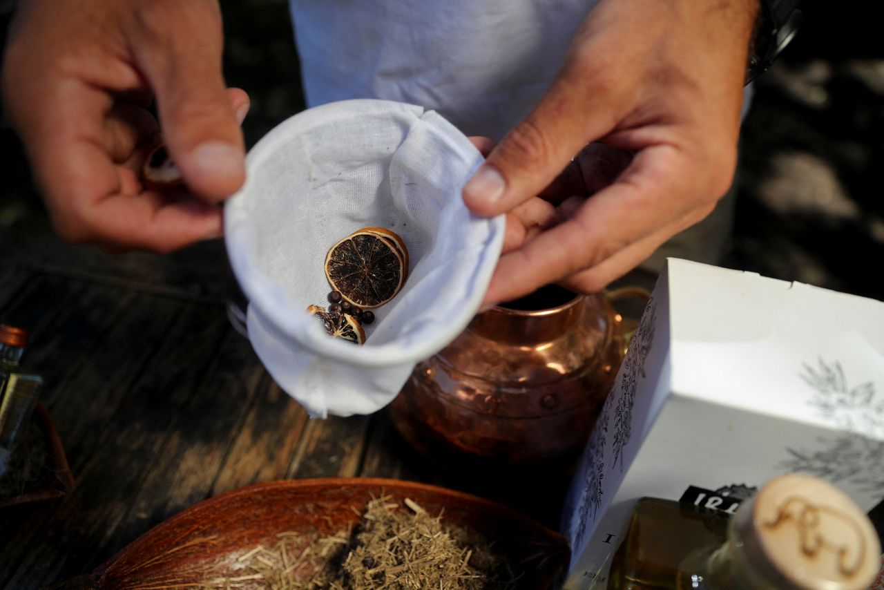 Les Ansley, owner of Indlovu Gin, holds a white cloth bag filled with botanicals extracted from dried elephant dung, used to make Indlovu gin, in Paarl, near Cape Town, South Africa, January 28, 2022. REUTERS/Sumaya Hisham