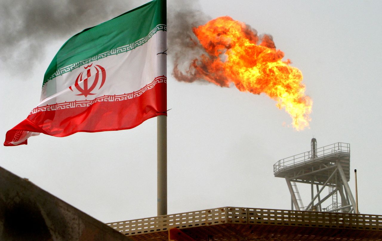 FILE PHOTO: A gas flare on an oil production platform is seen alongside an Iranian flag in the Gulf July 25, 2005. REUTERS/Raheb Homavandi