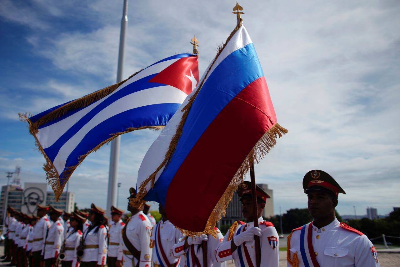 Honor guards hold a Russian and a Cuban flag during a wreath-laying ceremony with Russia