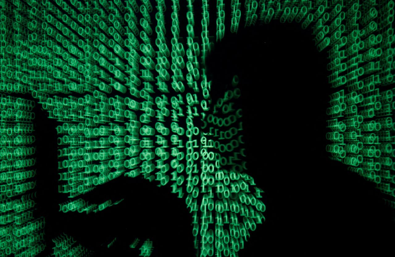 FILE PHOTO: A man holds a laptop computer as cyber code is projected on him in this illustration picture taken on May 13, 2017. REUTERS/Kacper Pempel/Illustration