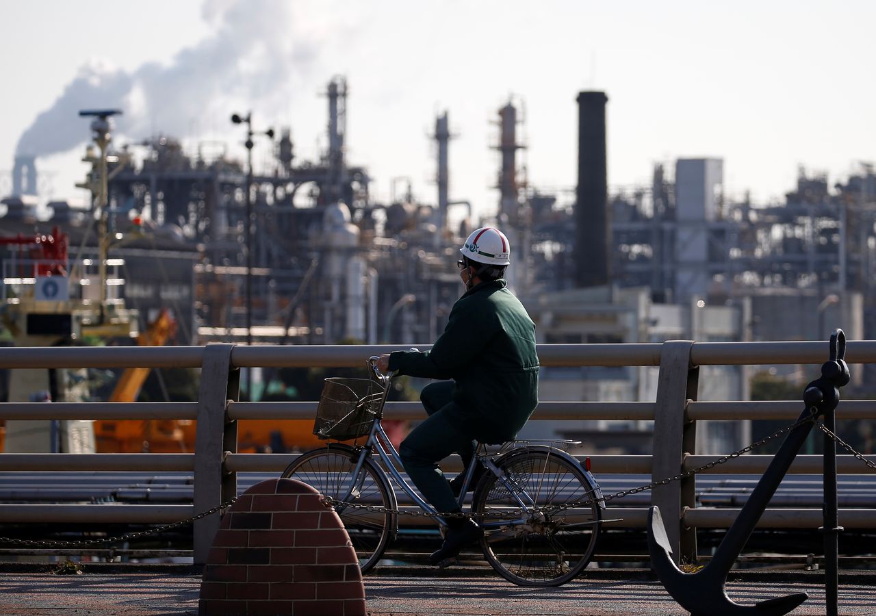 FILE PHOTO: A worker cycles near a factory at the Keihin industrial zone in Kawasaki, Japan February 28, 2017. REUTERS/Issei Kato
