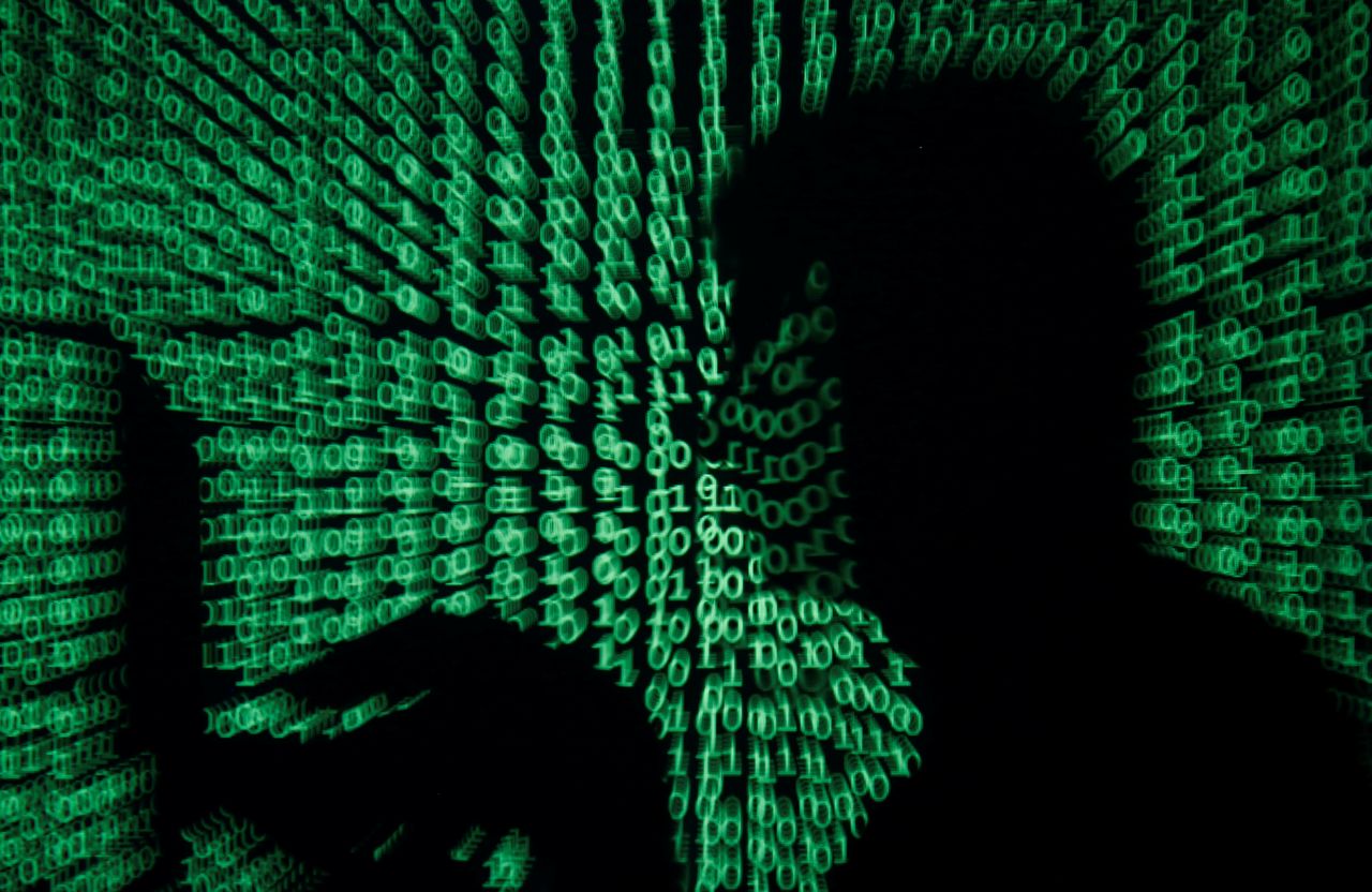 FILE PHOTO: A man holds a laptop computer as cyber code is projected on him in this illustration picture taken on May 13, 2017.  REUTERS/Kacper Pempel/Illustration