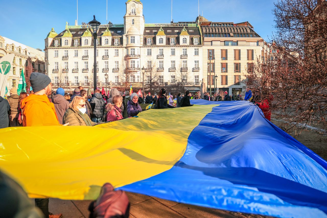 People unfold a flag of Ukraine to protest against Russia