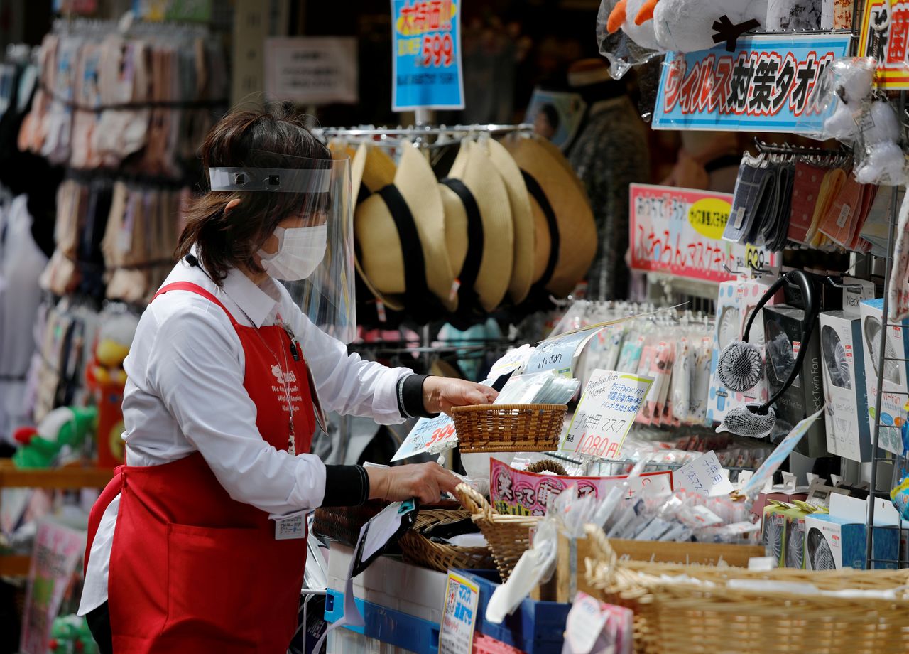 FILE PHOTO: An employee of a retail store wearing a protective face mask and a face mask is seen outside of the store under a nationwide state of emergency as the spread of the coronavirus disease (COVID-19) continues in Tokyo, Japan May 10, 2020. REUTERS/Issei Kato